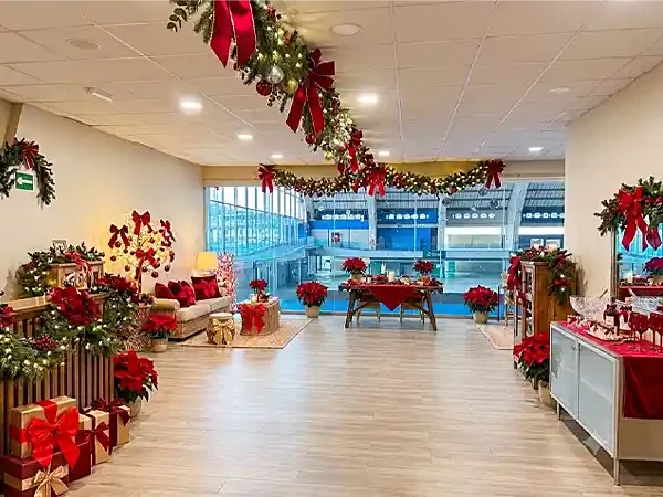 Zona lounge amplia con decoración navideña en tonos rojos, ideal para cócteles y eventos corporativos dinámicos.